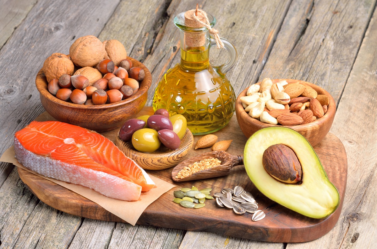 Mai multe alimente bogate în acizi grași omega-3 care mențin sănătatea creierului printre care un file de somon, avocado, uleiuri și migdale