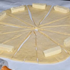 Aluat de cartofi secționat în triunghiuri, cu bucăți de brânză la bază