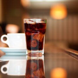 O cană de cafea pe un bar, alături de un pahar de suc acidulat reprezintă băuturile pe care este indicat să le eviți dacă ai peste 40 de ani
