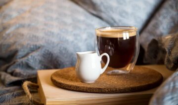 O ceașcă de cafea, servită la pat, alături de lapte