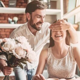 Un cuplu fericit care se află la o cafenea, în timp ce bărabtul îi oferă iubitei sale un buchet de flori