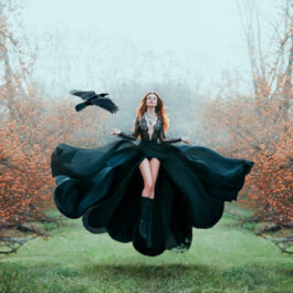 Fată frumoasă îmbrăcată într-o rochie neagră se află într-o pădure