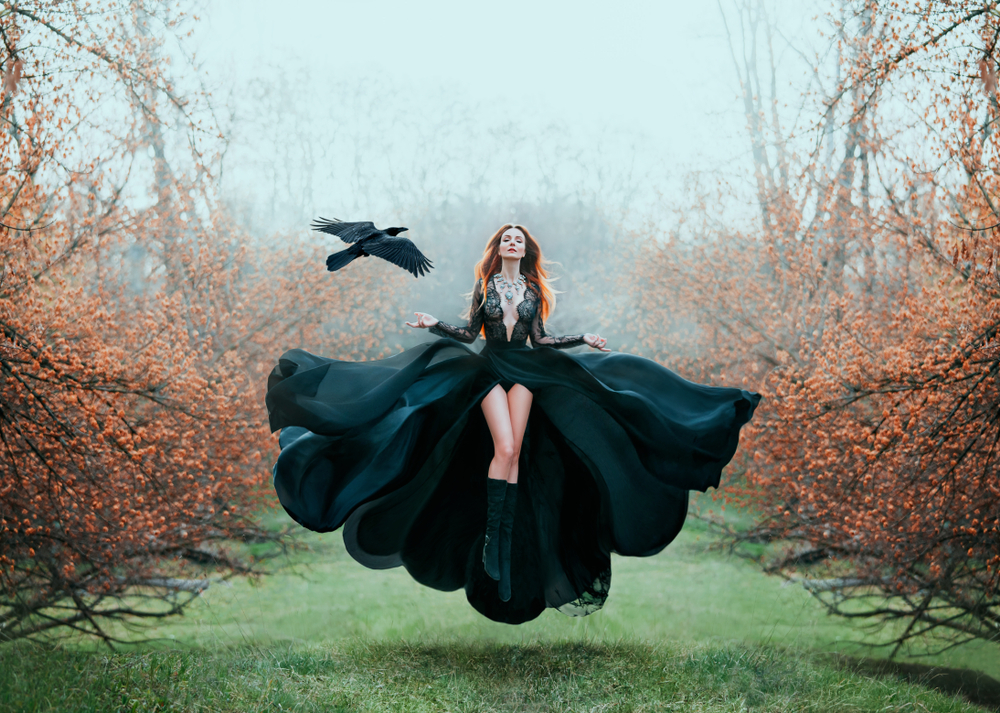 Fată frumoasă îmbrăcată într-o rochie neagră se află într-o pădure