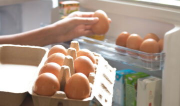 O femeie care pune ouăle pe suportul special din frigider