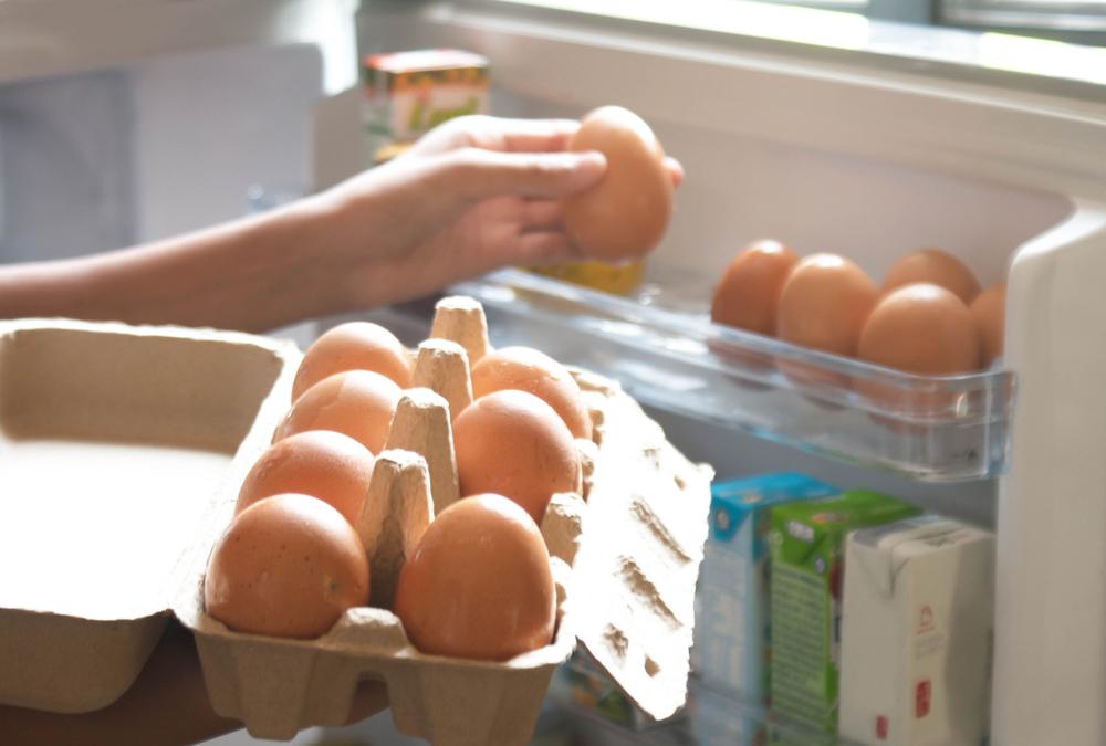 O femeie care pune ouăle pe suportul special din frigider