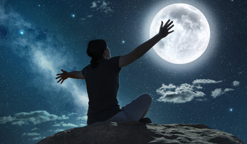 Fată stă cu fața către lună și cu mâinile întinde către aceasta