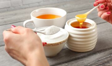 O imagine care sugerează că mierea poate fi un înlocuitor al zahărului pentru că este prezentată o cană de ceai albă, alături de două recipiente albe de ceramică ce conțin zahăr și miere.