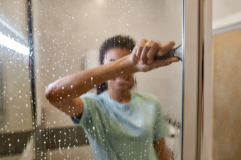 O femeie care curăță ușile de la cabina de duș