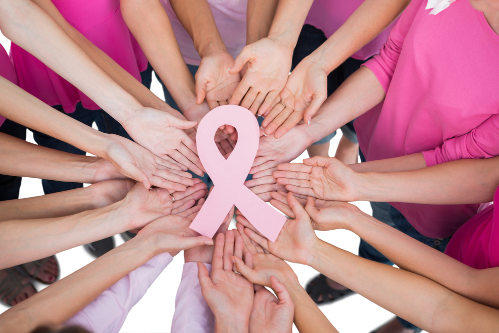 Mai multe femei care țin în mână simbolului împotriva cancerului de sân