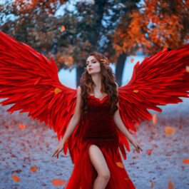O femeie frumoasă, îmbrăcată într-o rochie roșie, cu aripi