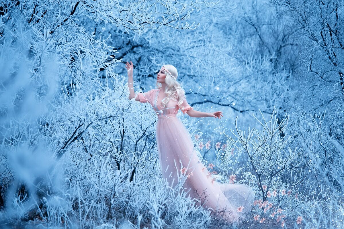 O femeie frumoasă într-o rochie albă care se află într-o pădure plină de zăpadă pentru a ilustra una dintre cele trei zodii norocoase pe 22 ianuarie 2023