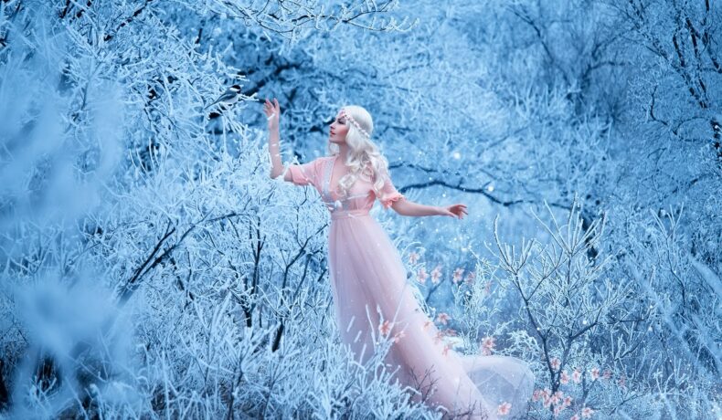 O femeie frumoasă într-o rochie albă care se află într-o pădure plină de zăpadă pentru a ilustra una dintre cele trei zodii norocoase pe 22 ianuarie 2023
