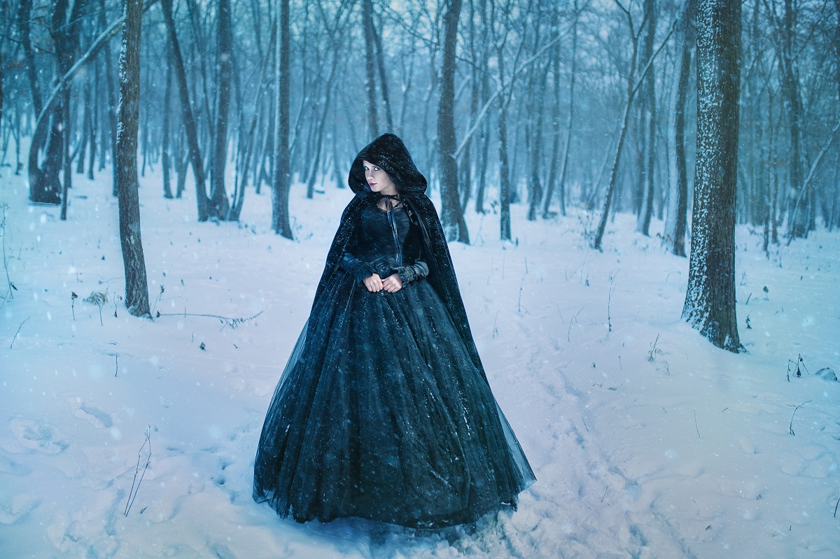 O femeie frumoasă într-o rochie neagră în timp ce se plimbă printr-o pădure cu zăpadă pentru a ilustra una dintre cele trei zodii răzbunătoare în ziua de 23 ianuarie 2023