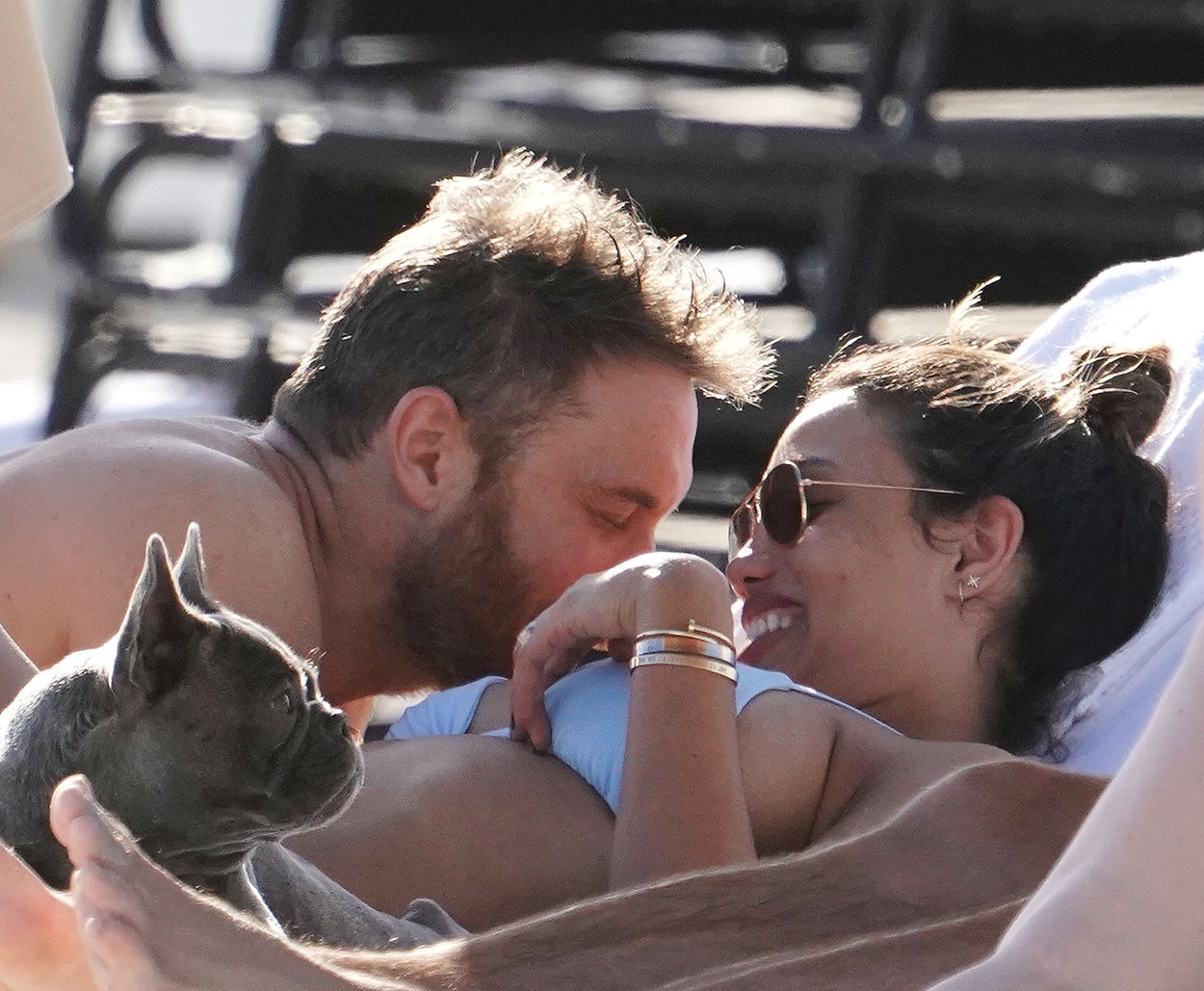 David Guetta, alături de iubita sa, pe un șezlong în timp ce o sărută, iar ea zâmbește