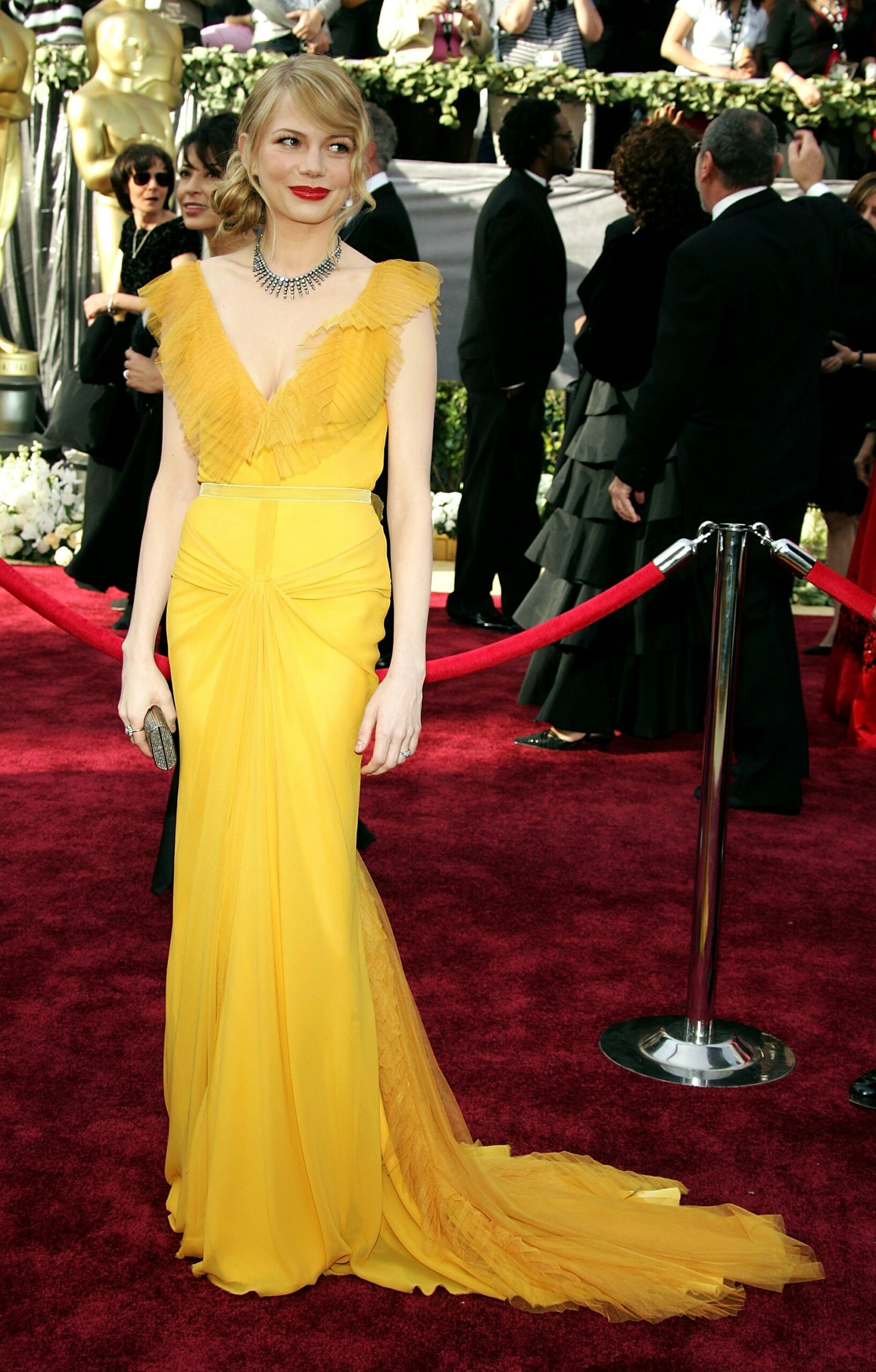 Michelle Williams într-o rochie de culoare galbenp, mulată și cambrată