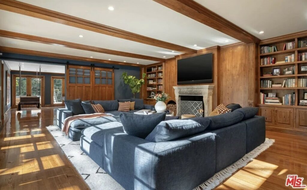 Camera de relaxare cu o canapea imensă, gri, un șemineu și un televizor mare din casa lui JLo din Bel Air