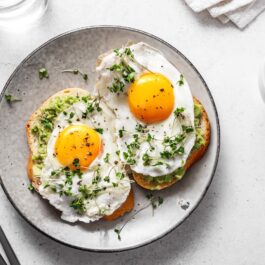 O farfurie frumoasă pe care se afl două ouă ochiuri pentru a ilustra ce se întâmplă în corpul tu dacă mănânci zilnic ouă