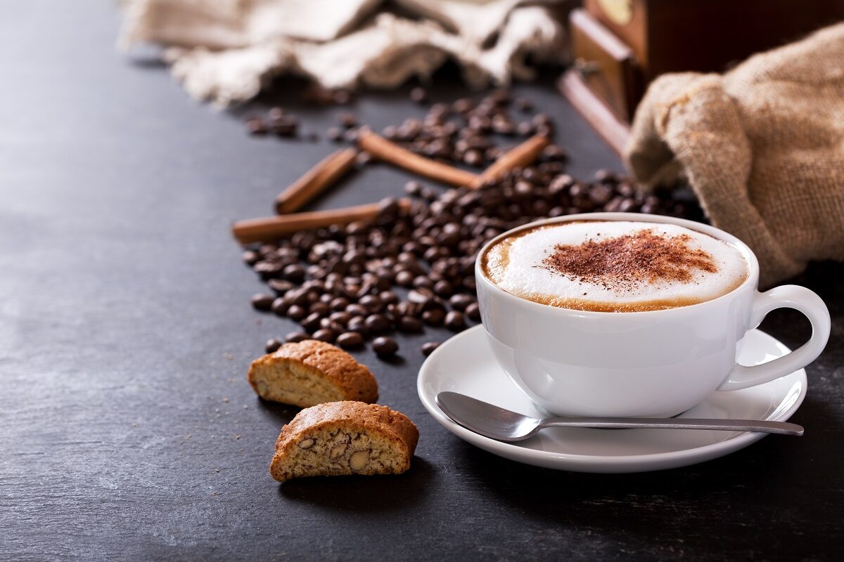 O ceașcă de cafea alături de câteva boabe de cafea pentru a ilustra cum aceasta te poate ajuta să pierzi în greutate