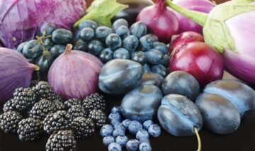 Fructe și legume de culoare mov printre care prune, afine, mure, struguri, vinete, ceapă roșie