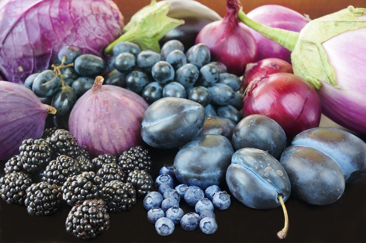 Fructe și legume de culoare mov printre care prune, afine, mure, struguri, vinete, ceapă roșie