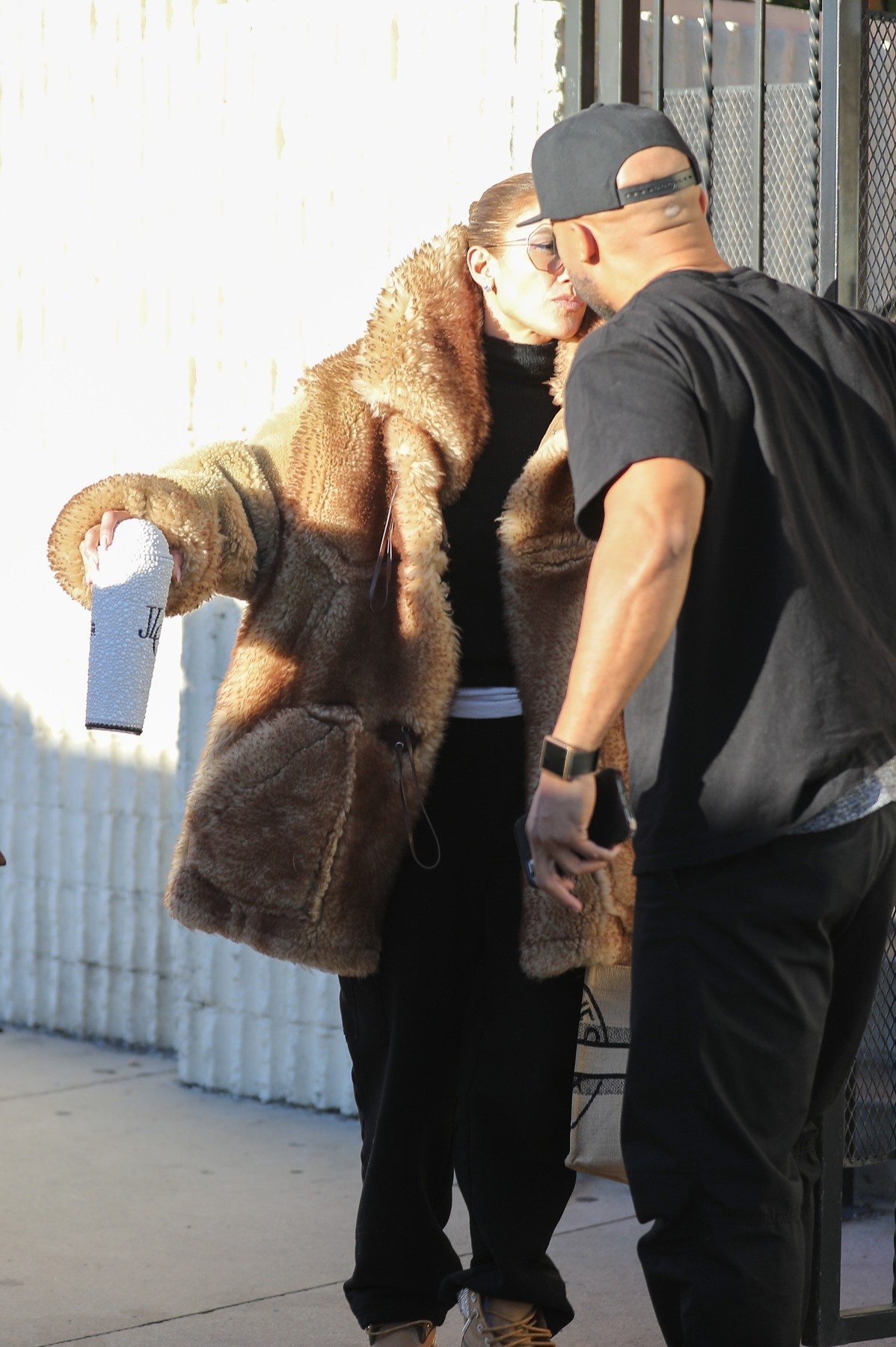 Jennifer Lopez în haină de blană în timp ce se sărută pe obraz cu un prieten pe străzile din Los Angeles