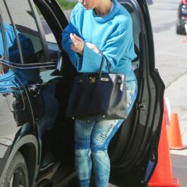 JLo, în colanți și pulovăr, albastre, lângă o mașină