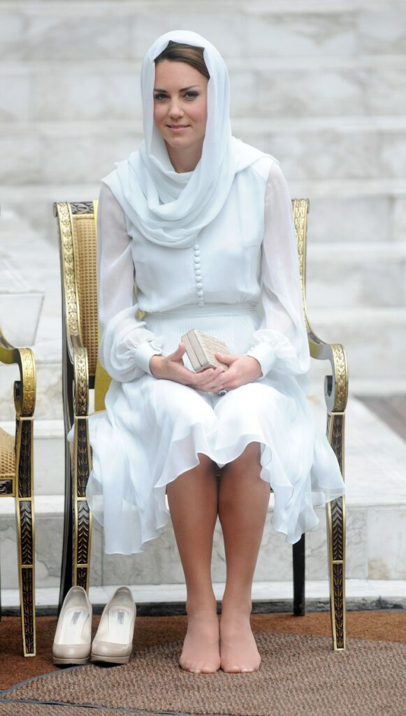 Kate Middleton poartă o rochie vaporoasă, albă și o eșarfă pe cap în timpul unui eveniment în Kuala Lumpur