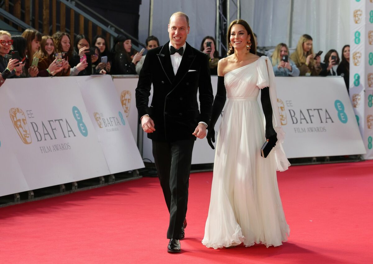 Kate Middleton poartă o rochie albă, vaporoasă, asortată cu o pereche de mănuși negre, înalte