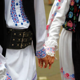 Un cuplu de români, în costume tradiționale, ținându-se de mână