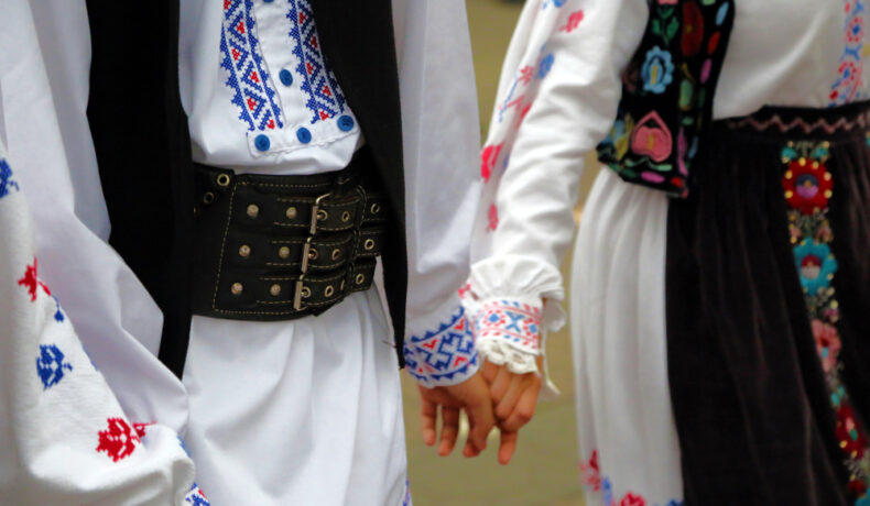 Un cuplu de români, în costume tradiționale, ținându-se de mână