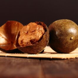 Două bucăți de monk fruit, una dintre ele este tăiată, acoperite de o coajă groasă de culoare maro