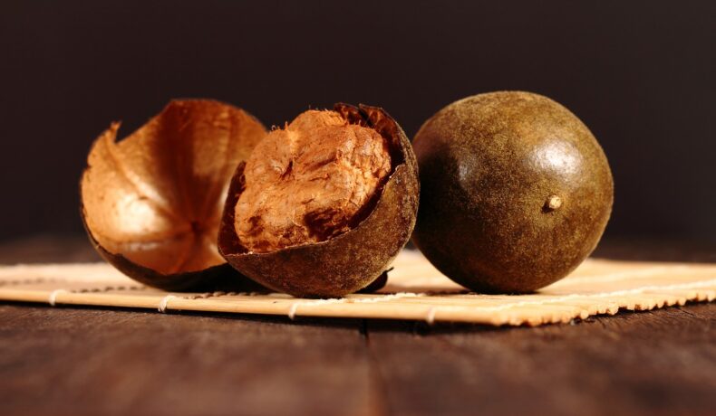 Două bucăți de monk fruit, una dintre ele este tăiată, acoperite de o coajă groasă de culoare maro