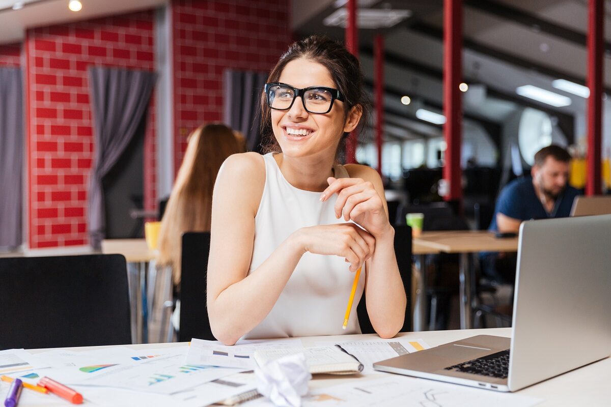 O femeie frumoasă care poartă ochelari și stă la birou pentru a putea ilustra câteva obiceiuri simple care să te ajute să ai o zi productivă