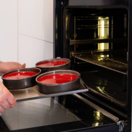Bărbat introducând în cuptor tava cu prăjituri de culoare roșie