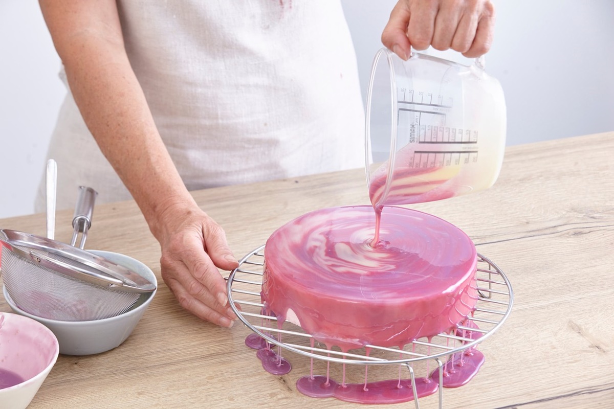 Femeie turnând glazură peste tort