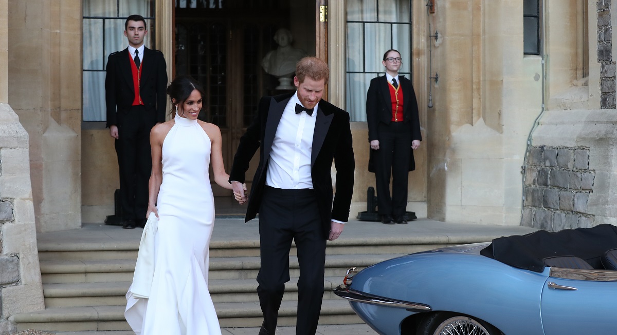 Meghan Markle într-o rochie albă alături de Prințul Harry, care poartă costum, în timp ce părăsesc castelul Windsor