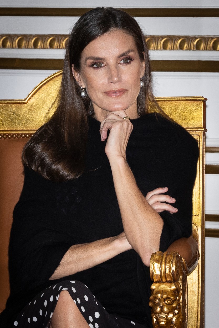 Regina Letizia, pe un scaun, cu mâna la bărbie, într-o haină neagră