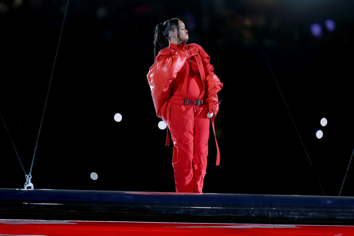 Rihanna se află pe scena de la Super Bowl 2023, îmbrăcată într-o vestimentație complet roșie care îi scoate în evidență sarcina