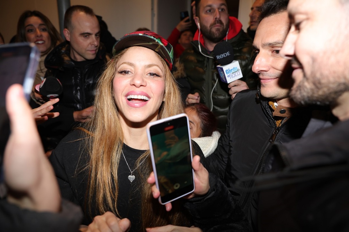 Shakira poartă o șapcă colorată pe cap și este asaltată de reporteri în cadrul unui eveniment