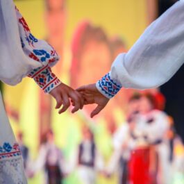 Un cuplu de tineri în costume populare românești care se țin de mână pentru a ilustra tradiții și superstiții de Dragobete