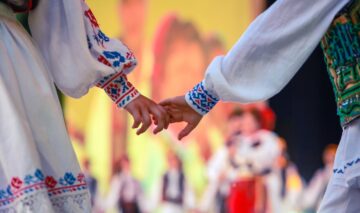Un cuplu de tineri în costume populare românești care se țin de mână pentru a ilustra tradiții și superstiții de Dragobete