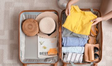 Un bagaj minimalist de vacanță ce cuprinde haine și pălării