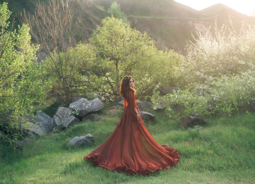 Fată frumoasă brunetă cu rochie lungă vișinie stă într-o pădure