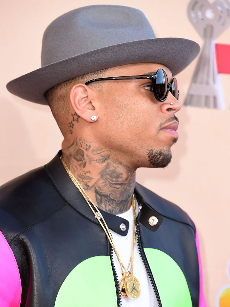 Chris Brown, cu o pălărie pe cap și ochelari de soare, la un eveniment