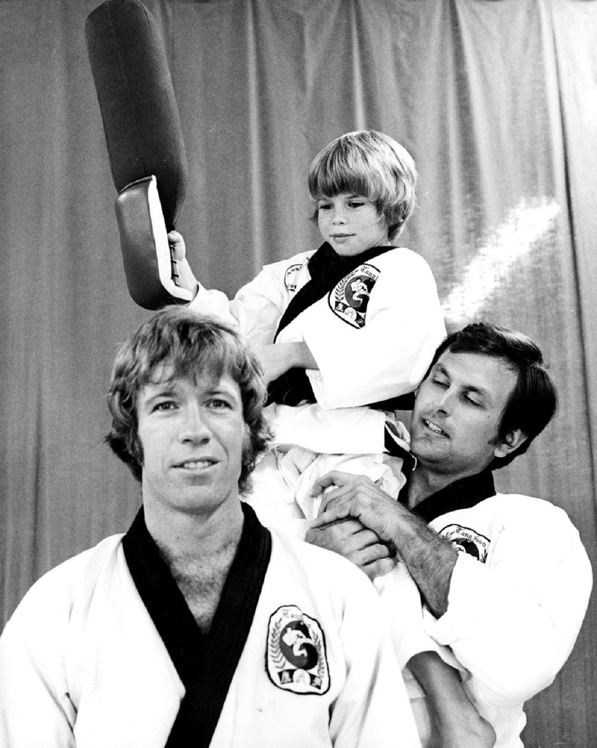 Chuck Norris alături de doi dintre clienții săi de la clubul de karate