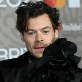 Harry Styles, într-un costum negru cu o bluză cu floare mare