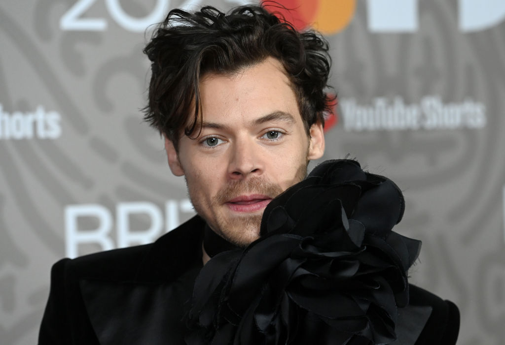 Harry Styles, într-un costum negru cu o bluză cu floare mare