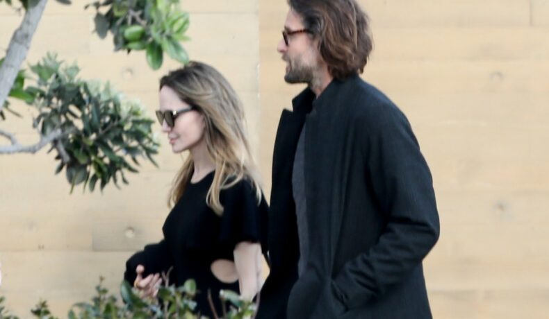 Angelina Jolie și David Mayer, zâmbind, pe stradă, îmbrăcați în haine lejere