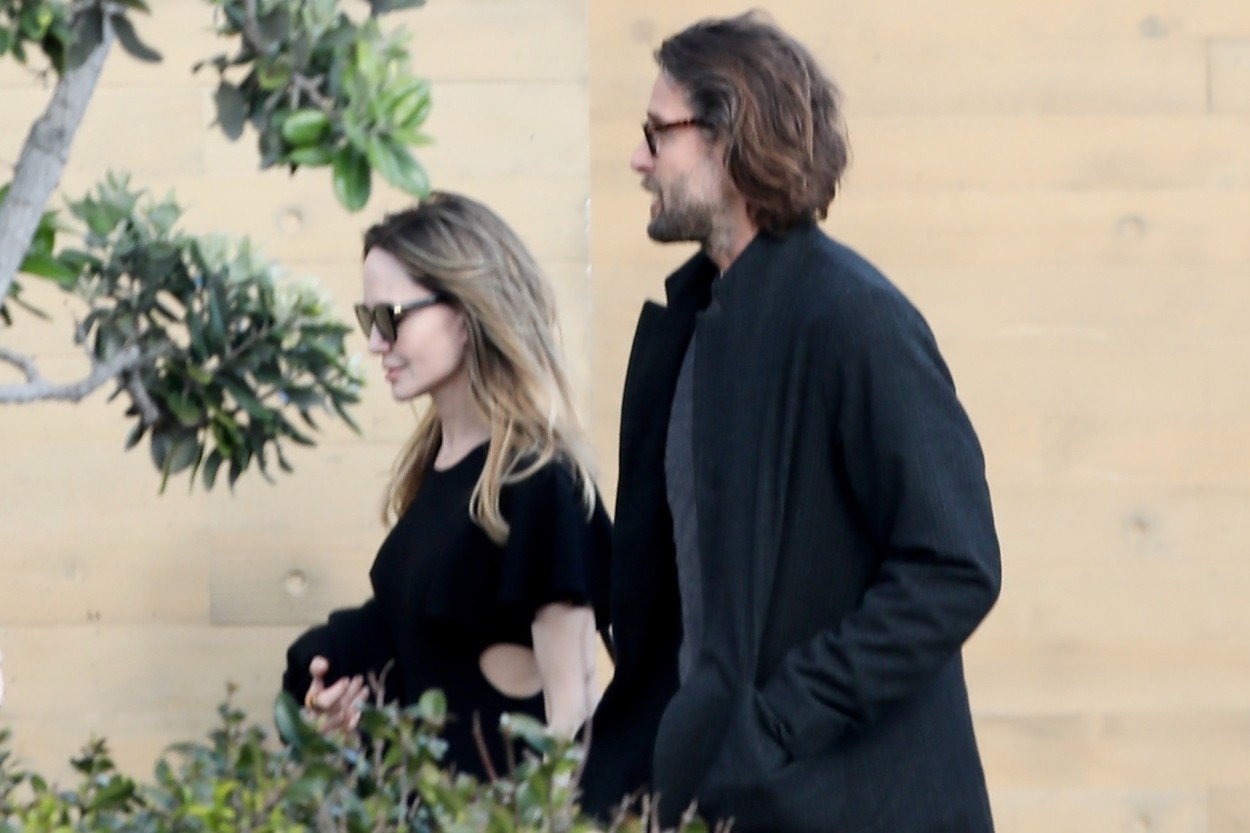 Angelina Jolie și David Mayer, zâmbind, pe stradă, îmbrăcați în haine lejere