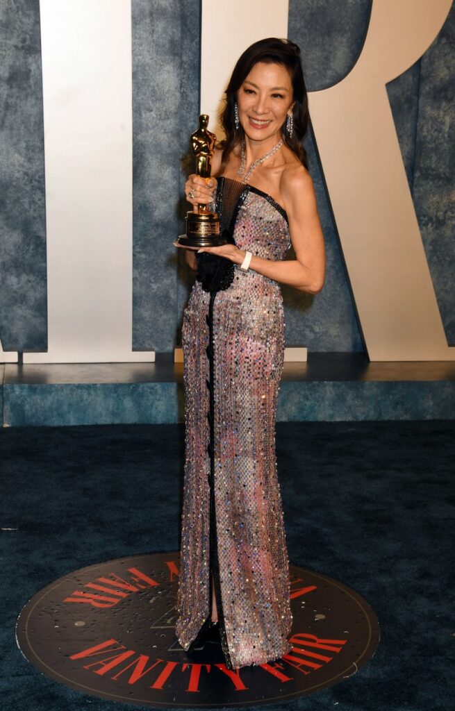 Michelle Yeoh, într-o rochie lungă, cu trofeul de la Oscar în mână, la petrecerea Vanity Fair Oscar Party 2023